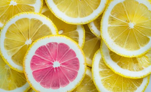 Übereinander liegende gelbe Zitronenscheiben. Eine Scheibe ist pink eingefärbt.